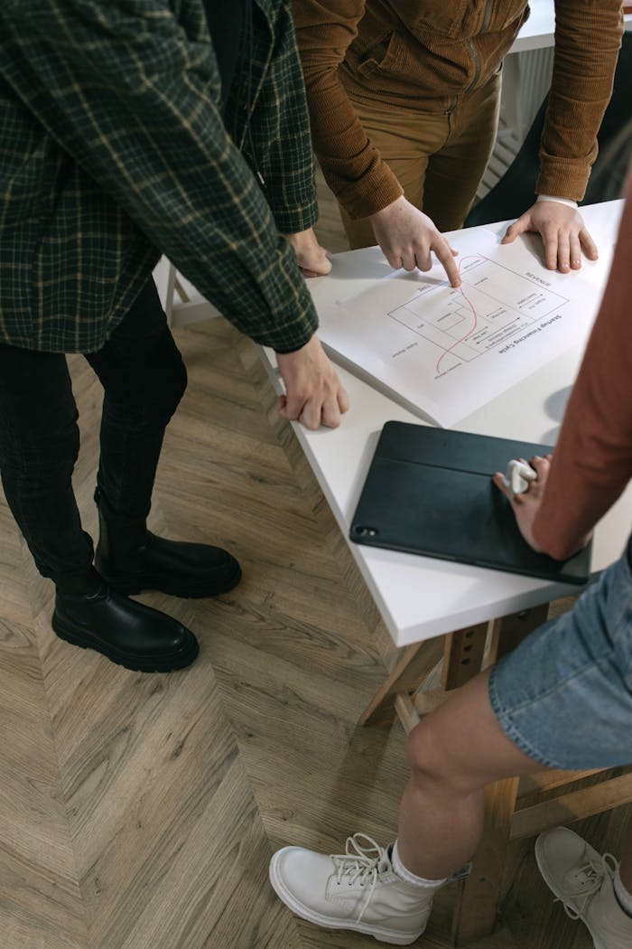 Top view of a team brainstorming at a desk with a chart, showcasing teamwork and planning skills.